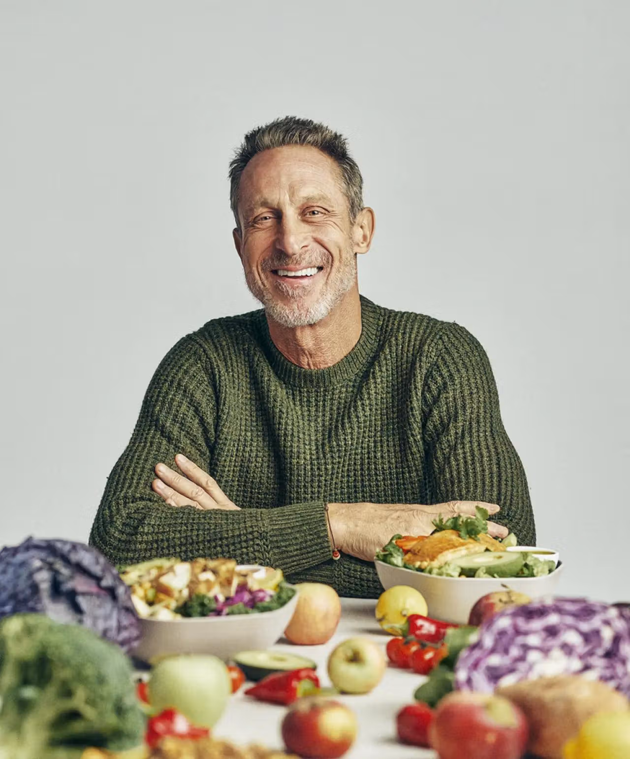 Mark Hyman sitting at a table with Sweetgreen bowls and fresh, healthy food.