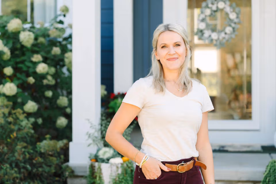 Erin standing outside in front of a house and smiling at the camera.