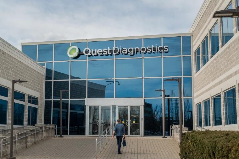 Person walking toward the glass entrance of a Quest Diagnostics lab building.