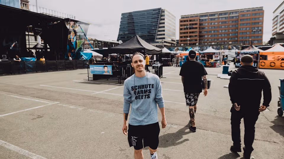 Cameron standing in an outdoor plaza with a concert stage and tents behind him.