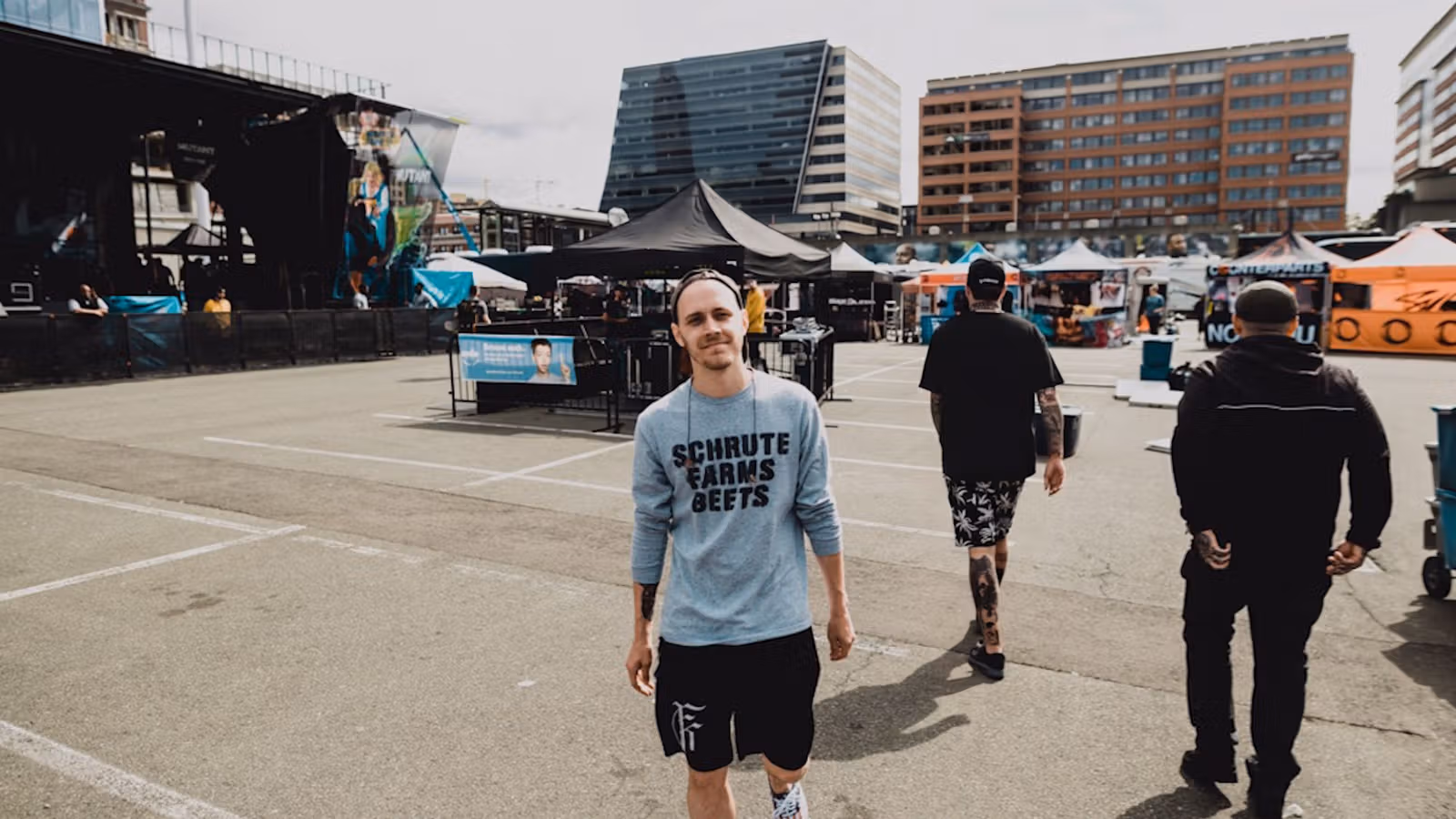 Cameron standing in an outdoor plaza with a concert stage and tents behind him.