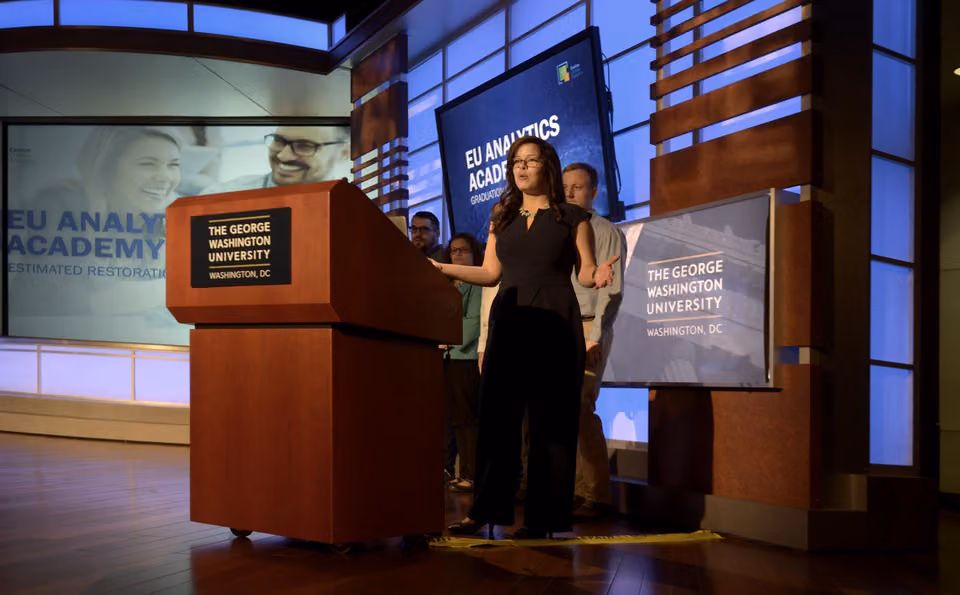 Sarah speaking on stage at a George Washington University Analytics Academy event.