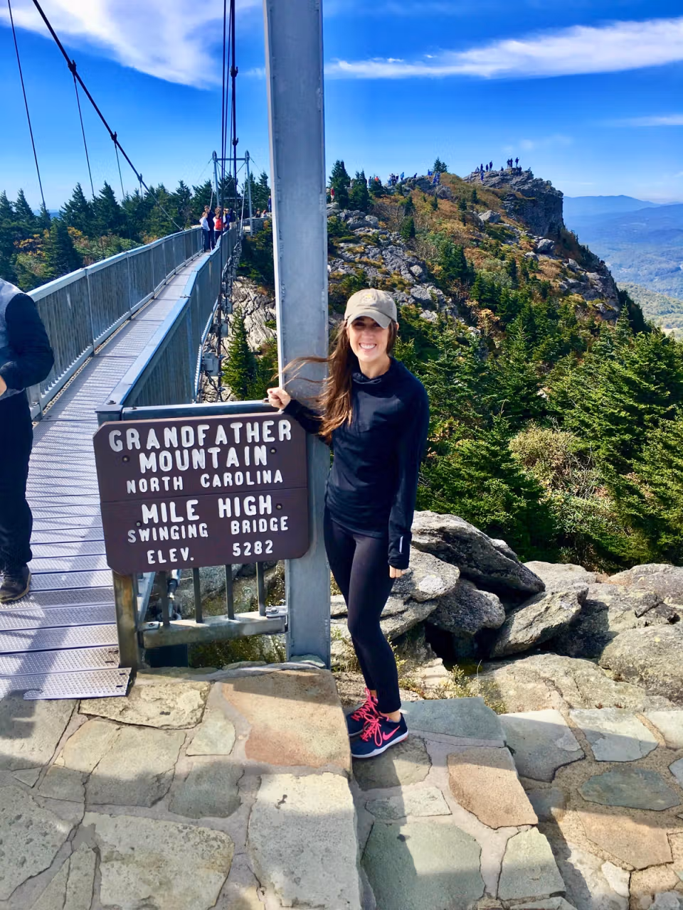 Jennifer standing beside a mountain bridge overlook and smiling at the camera.