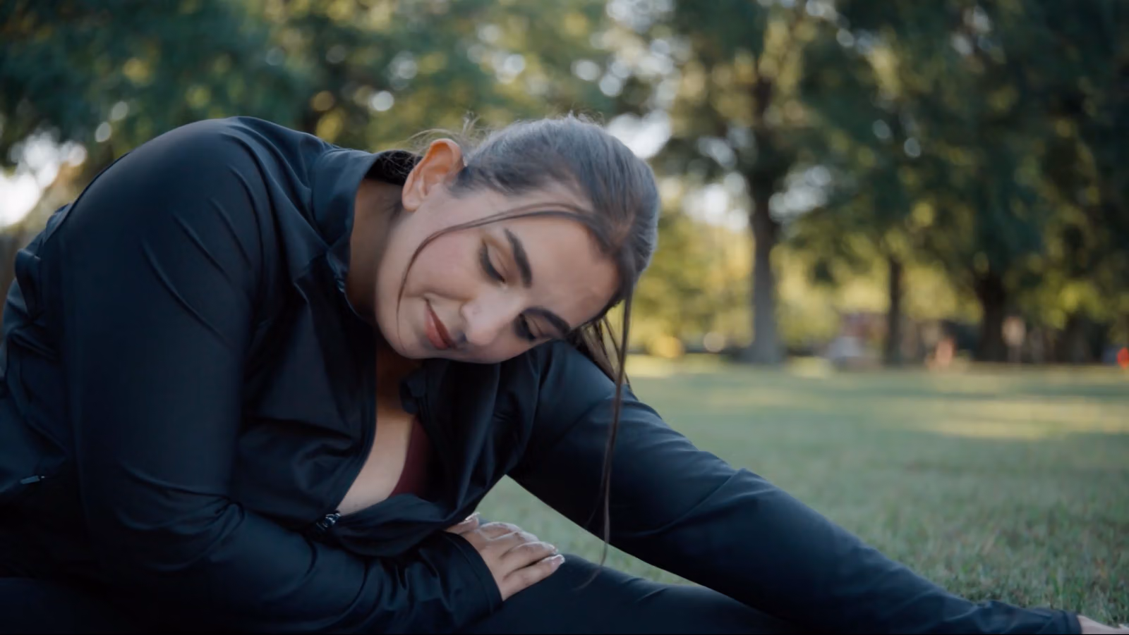 Sara stretching outdoors in a park.