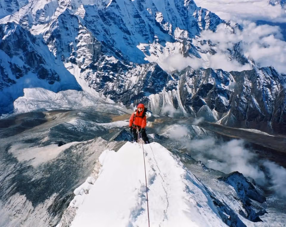 Wanda standing on a snowy mountain ridge with dramatic peaks in the background.