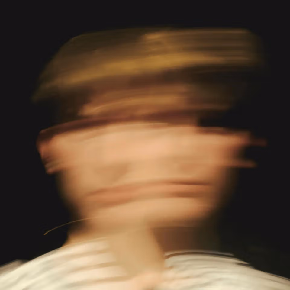 Blurred portrait of a person in motion against a dark background.